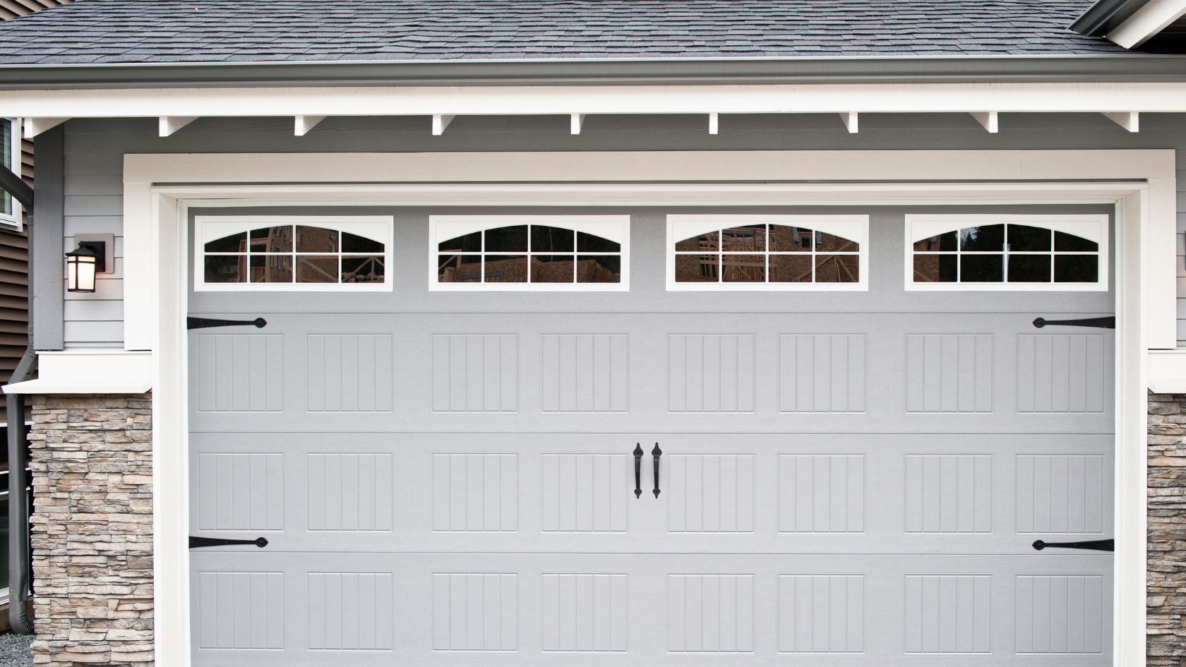 A gray garage door with windows on a house