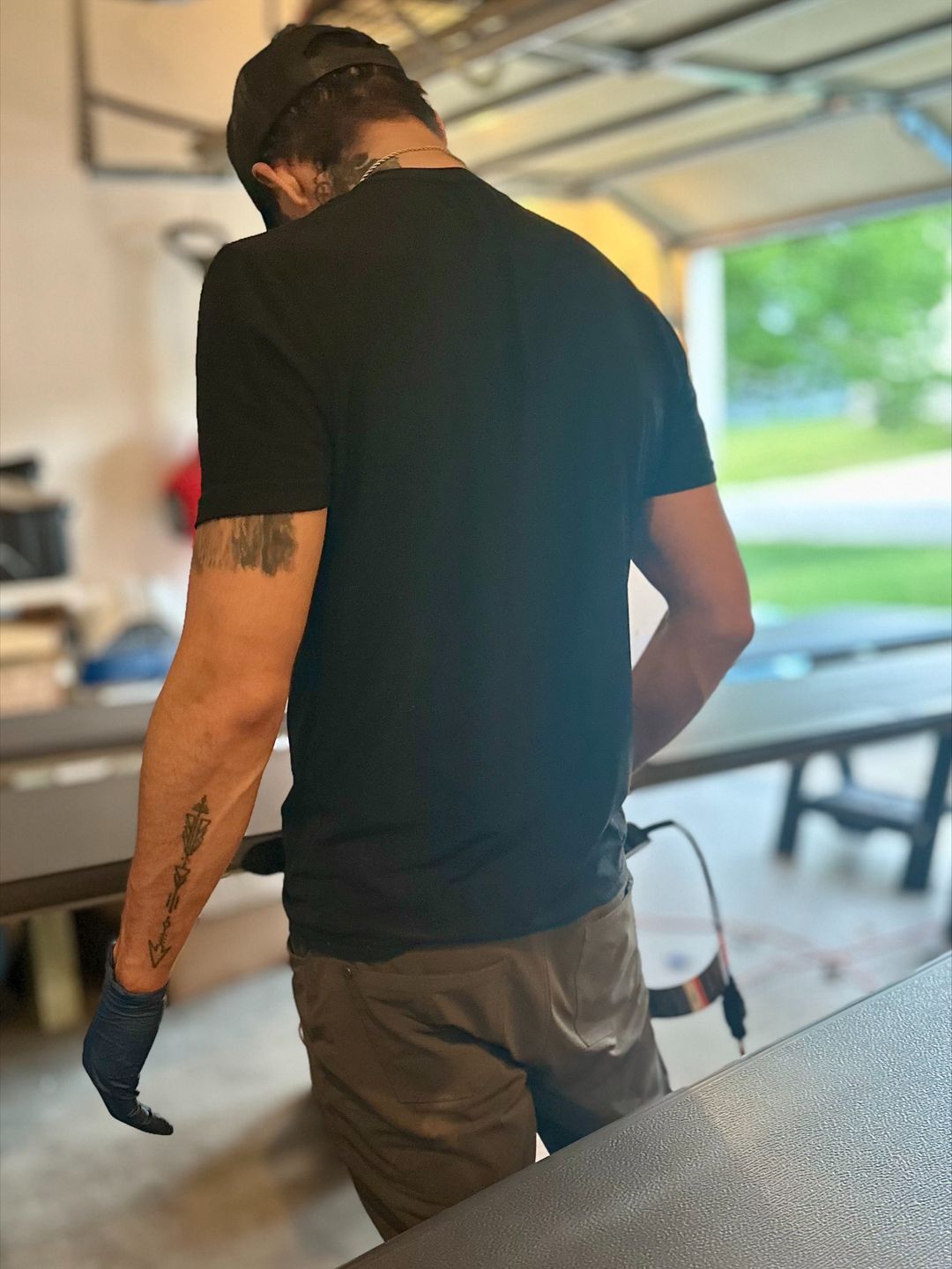 A man with a tattoo on his arm standing in a garage